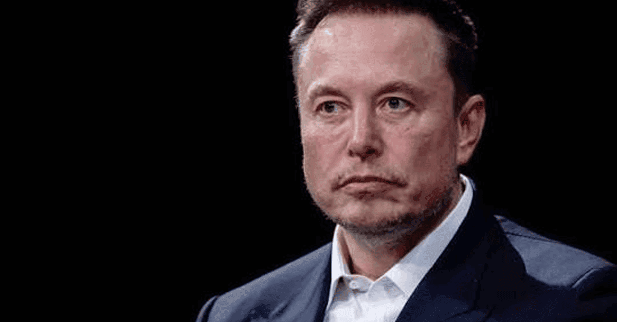 Elon Musk speaking at a tech conference, with AI graphics in background.